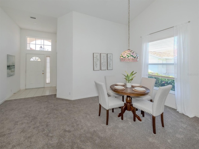 dining room featuring light colored carpet and a high ceiling