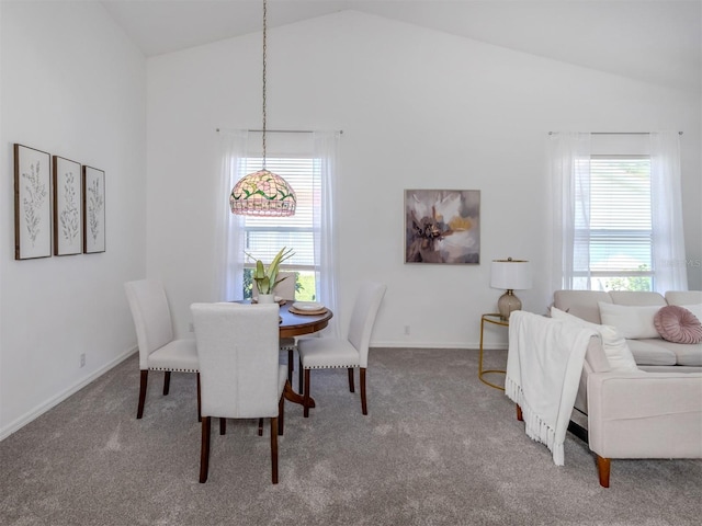 carpeted dining space with high vaulted ceiling