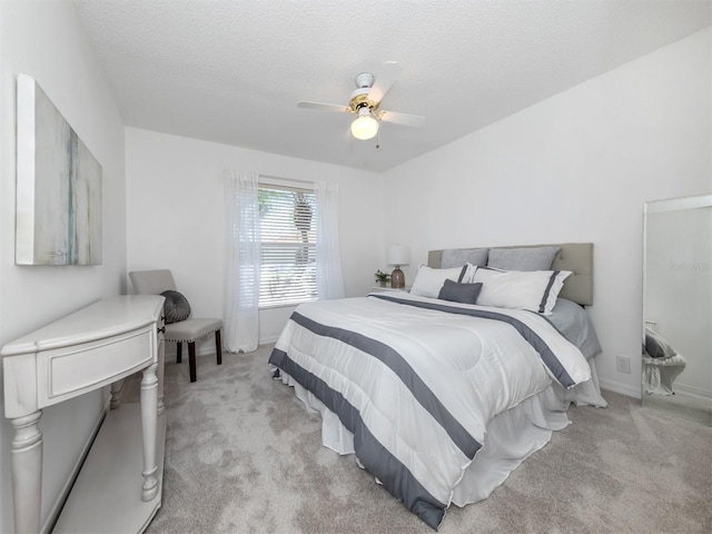 bedroom with a textured ceiling, light colored carpet, and ceiling fan