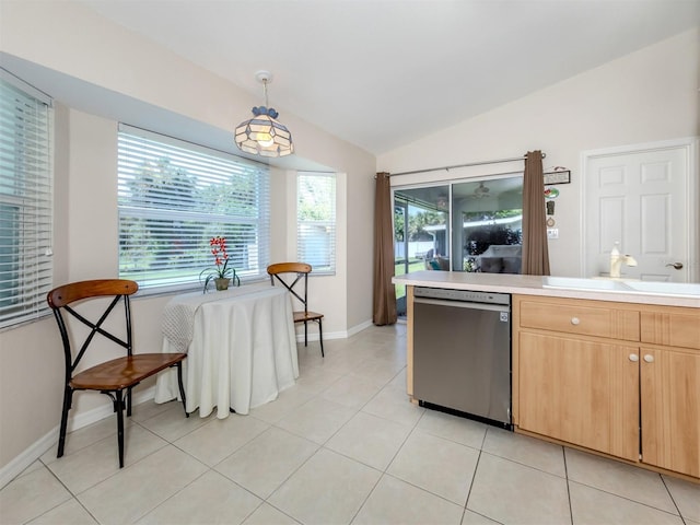 kitchen with pendant lighting, sink, lofted ceiling, light tile patterned floors, and stainless steel dishwasher