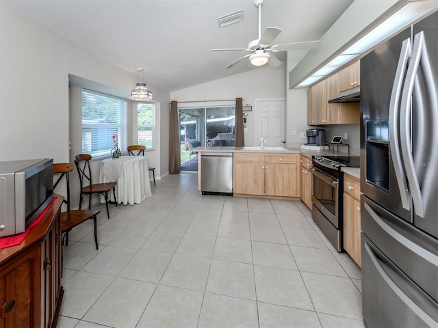 kitchen featuring vaulted ceiling, hanging light fixtures, light brown cabinets, appliances with stainless steel finishes, and light tile patterned floors