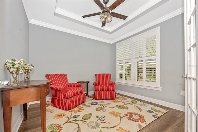 living area with a raised ceiling, crown molding, and wood-type flooring