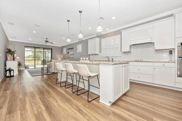 kitchen featuring pendant lighting, a center island, white cabinets, ceiling fan, and light stone countertops