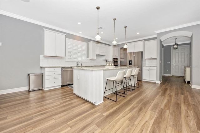 kitchen featuring appliances with stainless steel finishes, a center island, decorative light fixtures, and white cabinetry