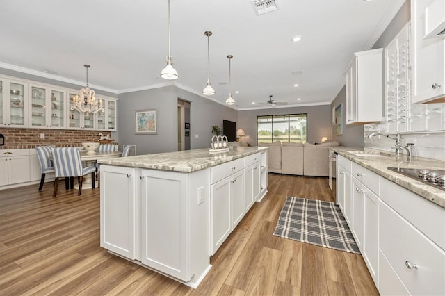 kitchen with a center island, ceiling fan with notable chandelier, light stone countertops, decorative light fixtures, and white cabinetry