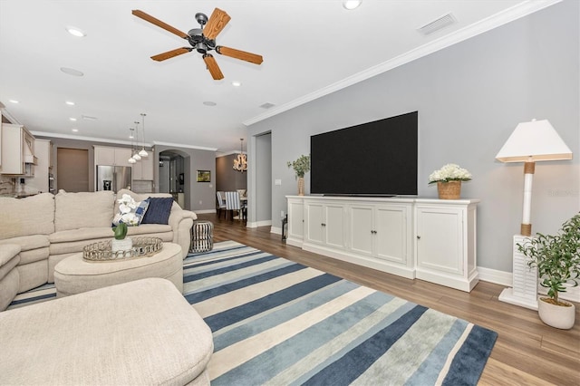 living room featuring light hardwood / wood-style flooring, ceiling fan with notable chandelier, and ornamental molding