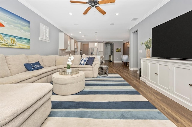 living room with dark hardwood / wood-style floors, ceiling fan, and crown molding