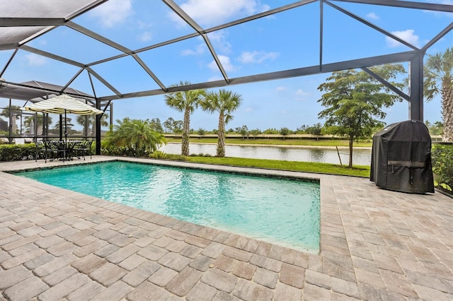 view of pool with glass enclosure, a water view, a patio, and grilling area