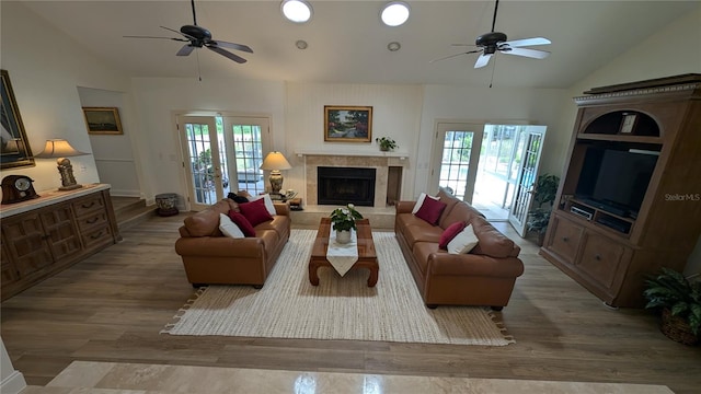 living room featuring a fireplace, hardwood / wood-style floors, french doors, ceiling fan, and vaulted ceiling