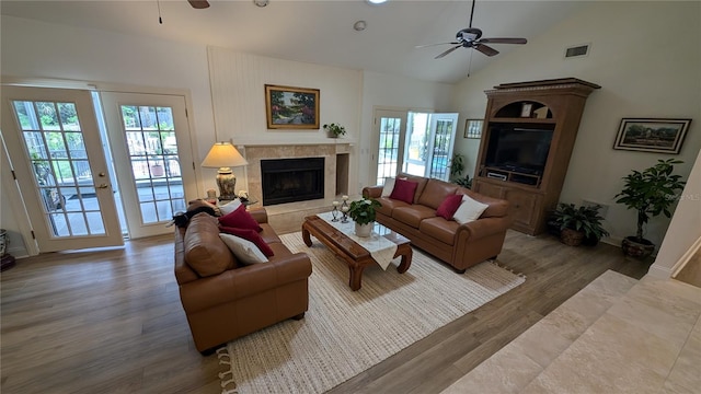 living room with high vaulted ceiling, wood-type flooring, ceiling fan, and a tile fireplace