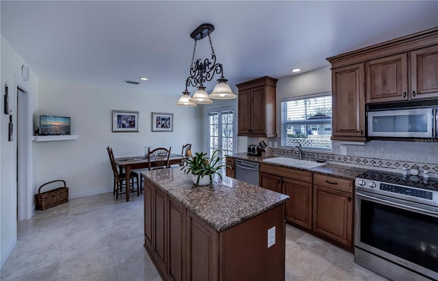 kitchen featuring a kitchen island, decorative light fixtures, appliances with stainless steel finishes, sink, and a chandelier