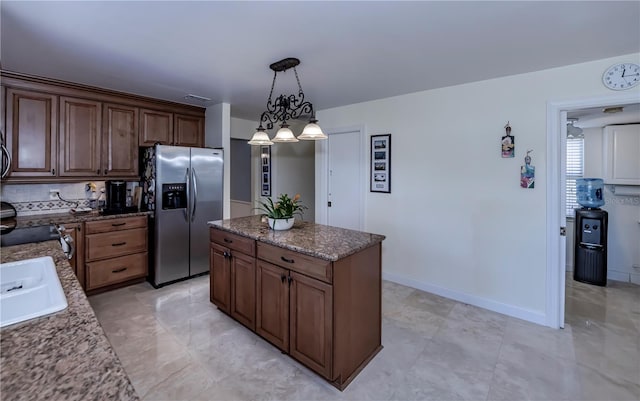 kitchen featuring a notable chandelier, stainless steel fridge with ice dispenser, hanging light fixtures, a center island, and dark stone counters