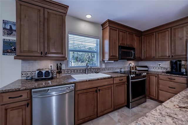 kitchen featuring sink, appliances with stainless steel finishes, stone counters, and decorative backsplash