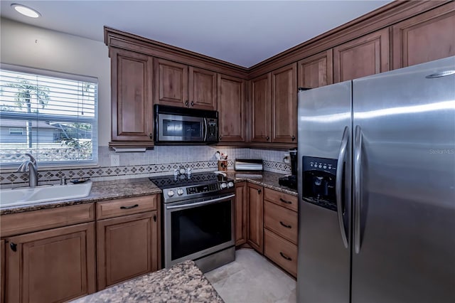 kitchen featuring appliances with stainless steel finishes, light tile patterned floors, backsplash, and sink