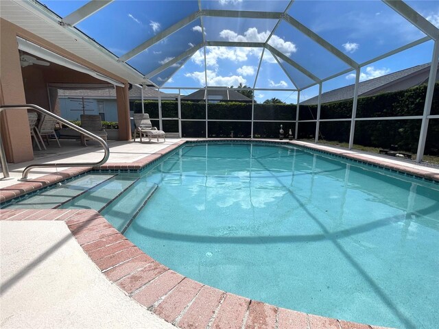 view of swimming pool with glass enclosure and a patio area