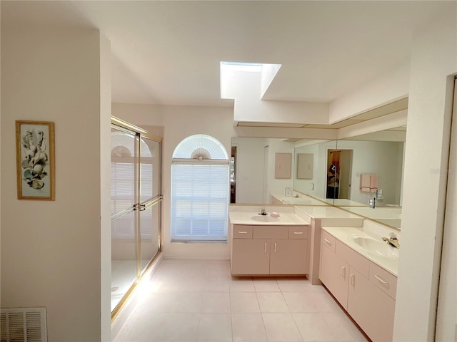 bathroom featuring tile patterned flooring, vanity, a shower with shower door, and a skylight