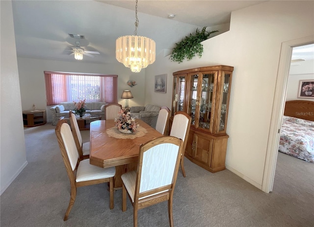 dining area with carpet flooring, ceiling fan with notable chandelier, and vaulted ceiling