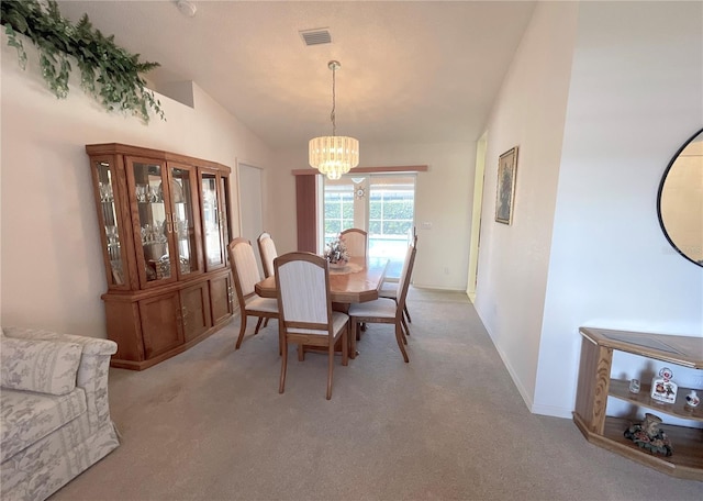 dining area with lofted ceiling, light colored carpet, and a notable chandelier