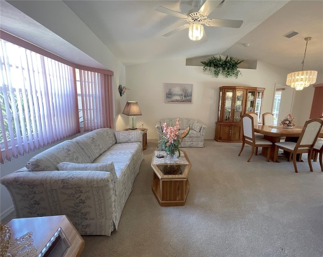 carpeted living room with ceiling fan with notable chandelier and vaulted ceiling