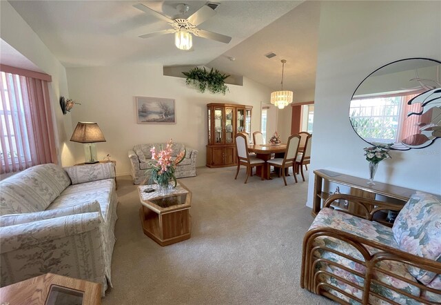 carpeted living room with ceiling fan with notable chandelier and vaulted ceiling