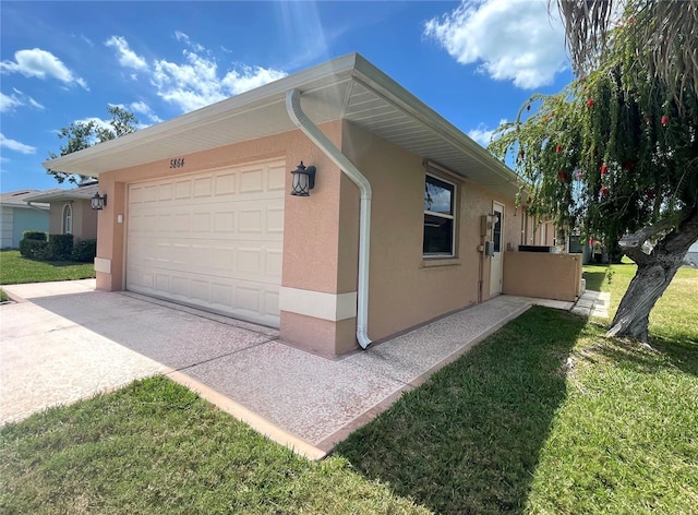 view of side of home with stucco siding, an attached garage, and a yard