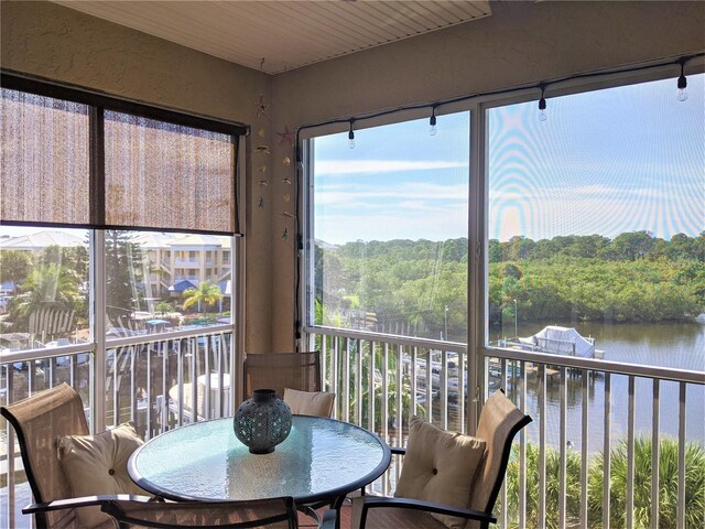 sunroom featuring a water view