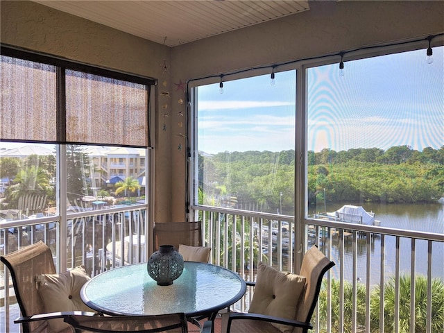 sunroom with a water view and a wooded view