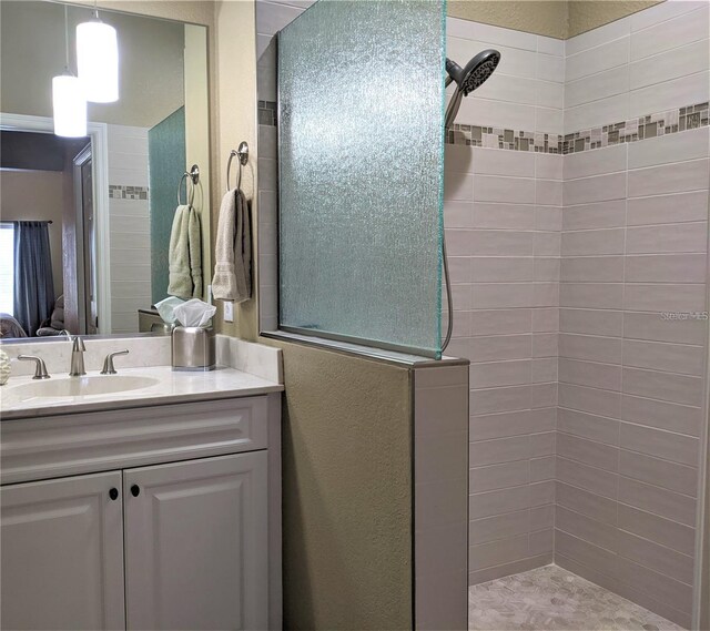 bathroom featuring tiled shower and vanity