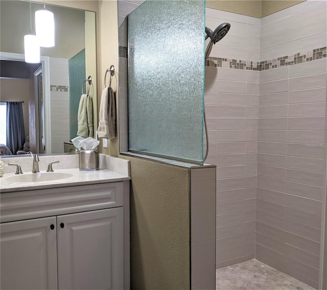 full bath with vanity, a textured wall, and walk in shower