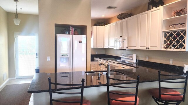 kitchen with white appliances, a breakfast bar area, sink, and decorative light fixtures