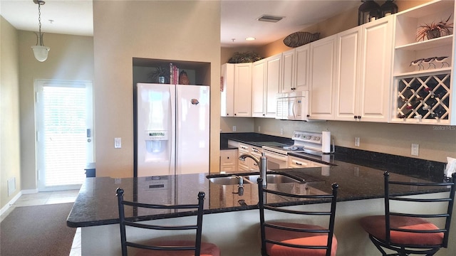 kitchen featuring visible vents, a sink, open shelves, white appliances, and hanging light fixtures