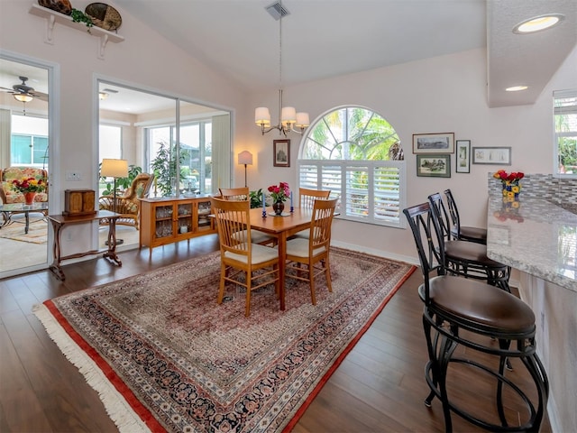 dining space featuring ceiling fan with notable chandelier, vaulted ceiling, dark hardwood / wood-style flooring, and a wealth of natural light