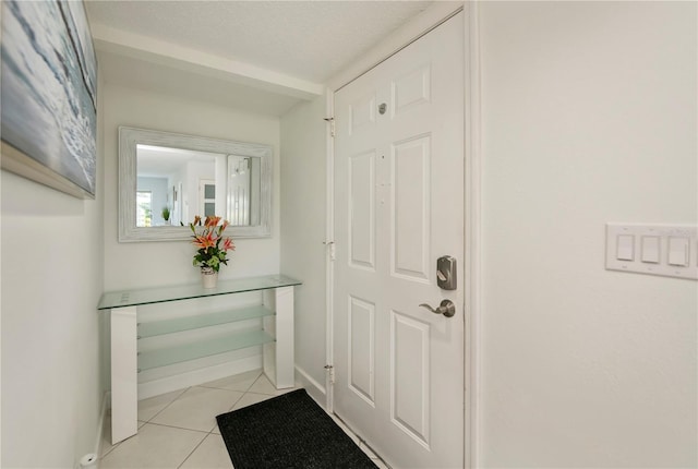 doorway to outside featuring light tile patterned floors and a textured ceiling