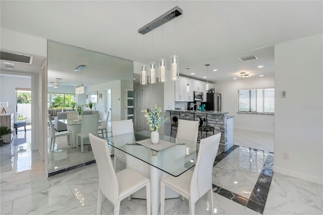 dining space with a textured ceiling, plenty of natural light, and ceiling fan