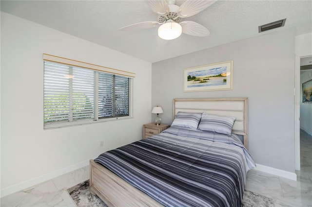 bedroom with ceiling fan and a textured ceiling