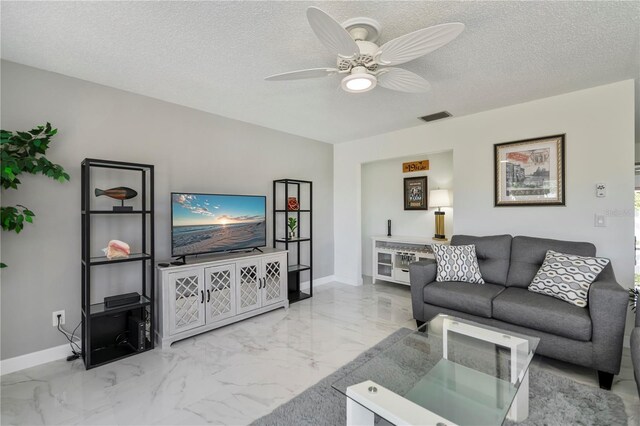 living room with ceiling fan and a textured ceiling