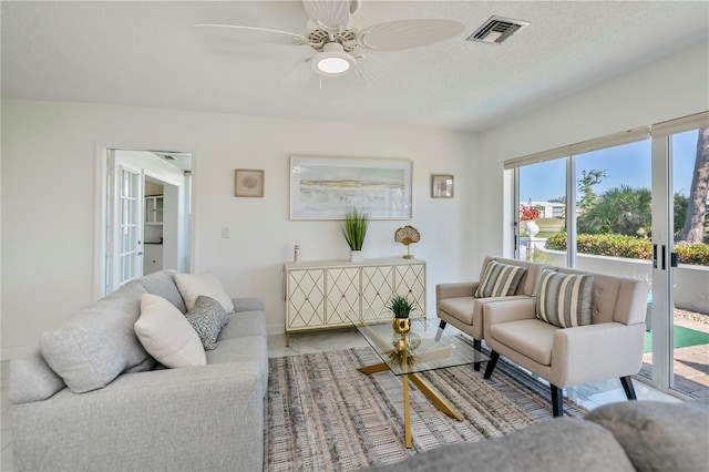 living room with french doors, a textured ceiling, and ceiling fan