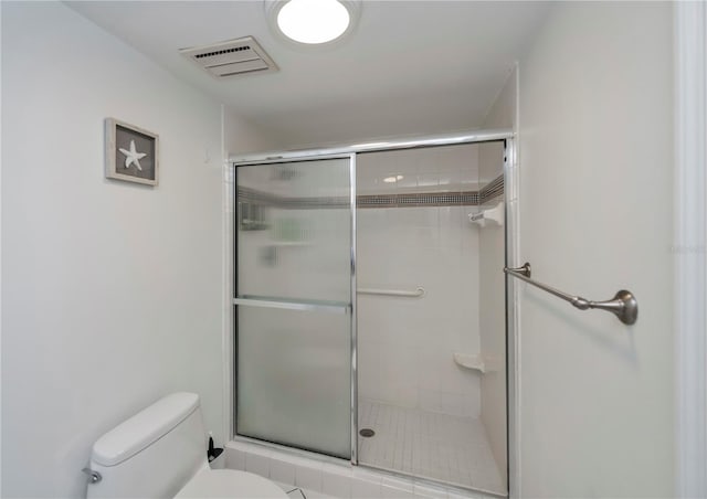 bathroom with tile patterned floors, toilet, and a shower with door