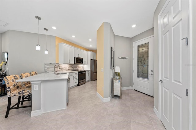 kitchen with white cabinets, sink, a breakfast bar area, kitchen peninsula, and stainless steel appliances