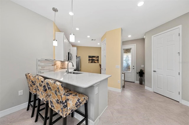 kitchen featuring kitchen peninsula, sink, pendant lighting, white cabinets, and a breakfast bar area