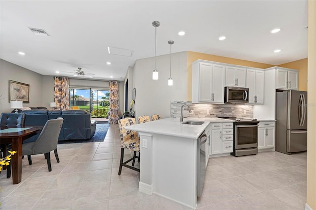 kitchen featuring sink, kitchen peninsula, decorative light fixtures, white cabinetry, and stainless steel appliances