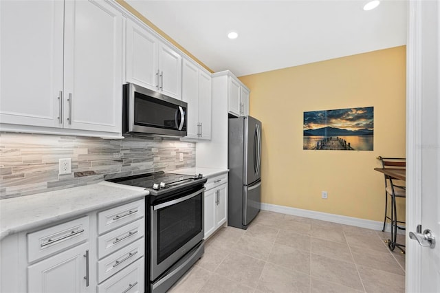 kitchen with backsplash, light stone counters, stainless steel appliances, light tile patterned floors, and white cabinets