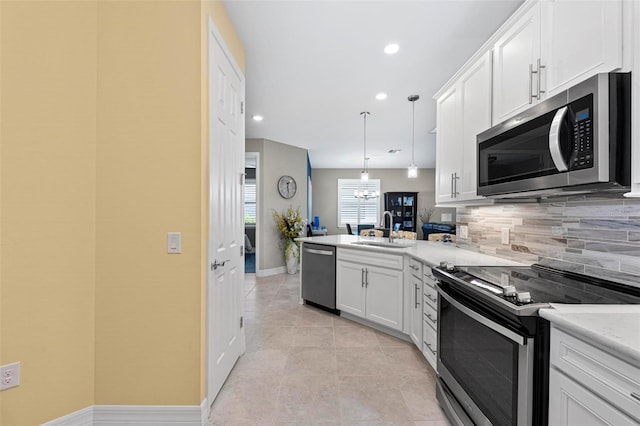 kitchen with kitchen peninsula, stainless steel appliances, sink, decorative light fixtures, and white cabinetry