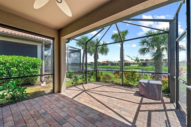 unfurnished sunroom featuring a water view and ceiling fan