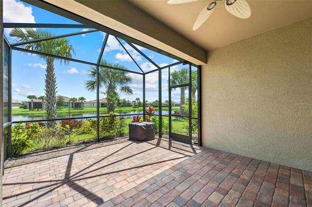 unfurnished sunroom featuring ceiling fan and a water view