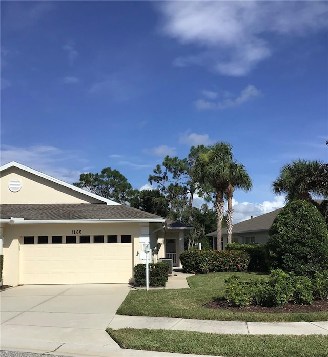 view of front of home featuring a garage, concrete driveway, a front lawn, and stucco siding