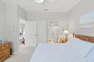 carpeted bedroom with ensuite bath and ceiling fan