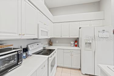 kitchen with white cabinets, white appliances, and light tile patterned flooring