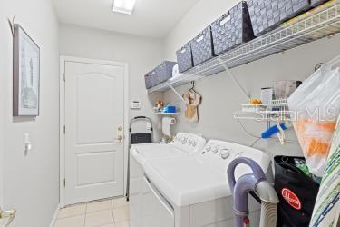 laundry area with washer and clothes dryer and light tile patterned floors