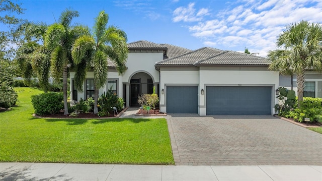 mediterranean / spanish home with decorative driveway, a tile roof, stucco siding, a garage, and a front lawn